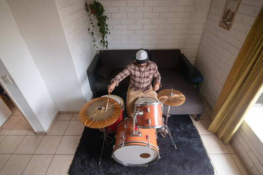 A top-down view of a man playing the drums at home