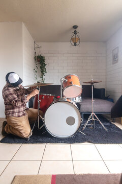 A man setting up an acoustic drum set in his living room