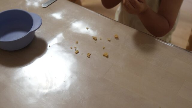 Close-up of a toddler eating cereal flakes from a bowl at the table