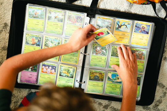 Chicago, IL/USA - August 3, 2026: Child organizing Pok&eacute;mon trading cards inside an open collector binder during a card sorting session