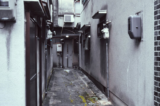 Narrow alley between buildings with exposed pipes, Japan