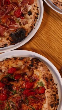 Overhead View of Gourmet Neapolitan Pizzas on a Wooden Restaurant Table