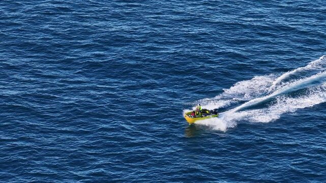 Aerial View of Yellow Powerboat Speeding Across Blue Ocean