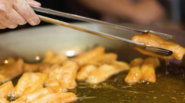 Chef Frying Traditional Asian Dough Sticks in Hot Oil Wok