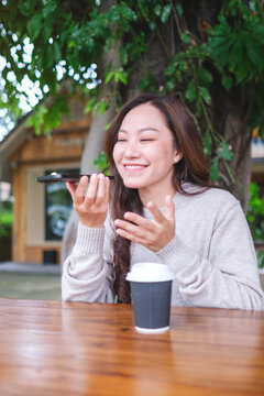 Vertical image of a woman holding smart phone and using voice messaging, talking with ai assistant for Artificial intelligence concept
