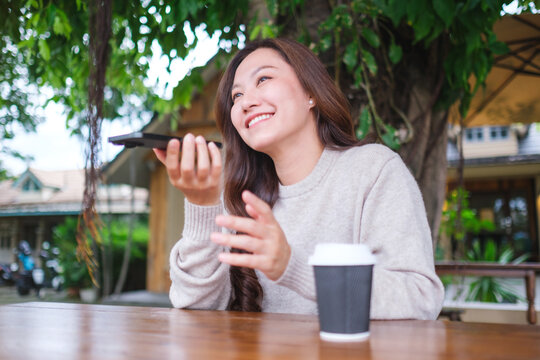 A woman holding smart phone and using voice messaging, talking with ai assistant for Artificial intelligence concept