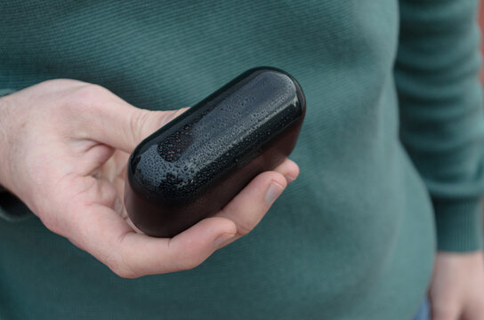 Estuche de auriculares inal&aacute;mbricos mojado con gotas de agua sobre la superficie