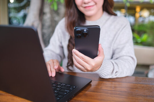 Closeup image of a businesswoman using smart phone and laptop computer