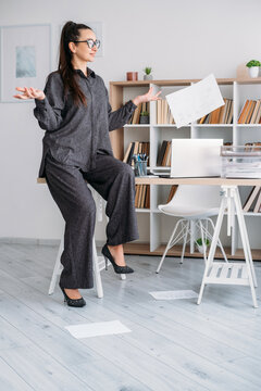 Carefree business manager. Paperwork routine. Relaxed woman professional throwing away papers at desk at modern office.