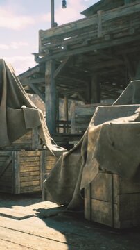 Under soft sunlight, weathered wooden crates sit quietly, draped in fabric. The rustic setting reveals hints of a past bustling market, evoking a sense of nostalgia and mystery.