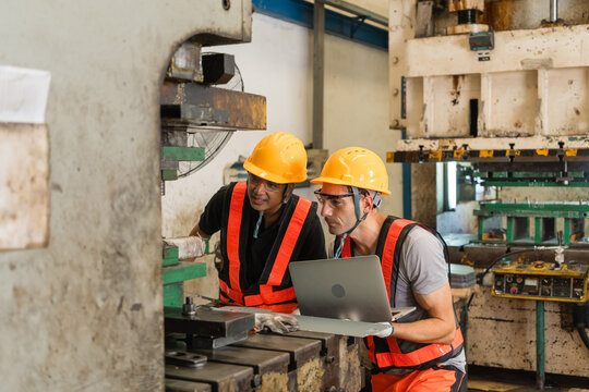 Engineer and technician giving thumbs up beside die of aging stamping press