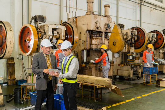 Senior Manager And Engineer Reviewing Production Data On Tablet Beside Stamping Press