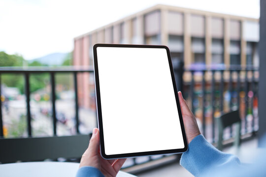 Mockup image of a woman holding digital tablet with blank white desktop screen in cafe