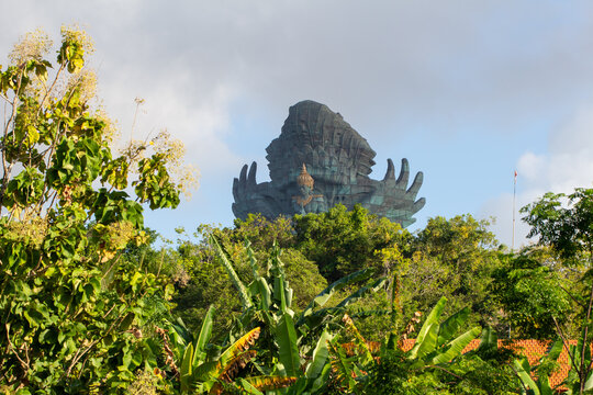 Colossal Garuda Wisnu Kencana statue of Vishnu on the Garuda rising above green treetops, GWK Park, Ungasan, Bali, Indonesia.