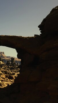 Majestic rock formation rises high in a vast desert landscape, while warm sunlight illuminates the rugged textures of the stone. A moment of natural beauty captured in time.