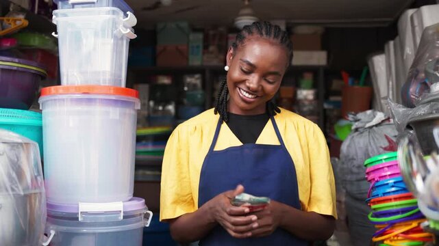 Successful African woman entrepreneur holding money in her small business shop, SME