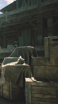 Rustic crates sit stacked at a charming coastal dock. Sunlight streams down, casting gentle shadows on the gray cloth draped over them, hinting at untold stories.