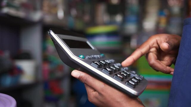 African female entrepreneur using a calculator for financial management in her store