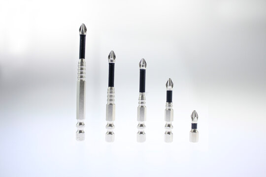 Set of five metal screwdriver bits arranged in descending sizes and isolated on a clean white background. Interchangeable drill driver accessories featuring metallic hex shanks, and precision formed 