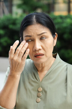 Middle aged Asian woman touching eyelid bump old aged health condition