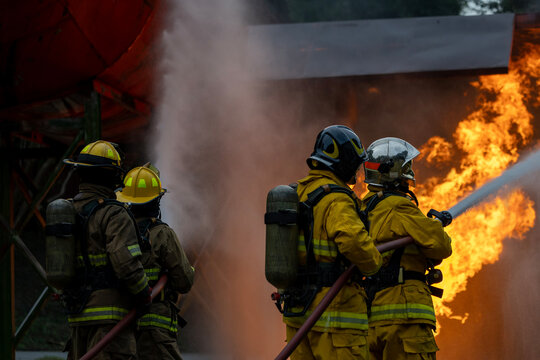 Team of firefighter in fireproof cloth using fog watering hose to put out the burning crashing plane with high flame for fire extinguish risk rescue mission and accident