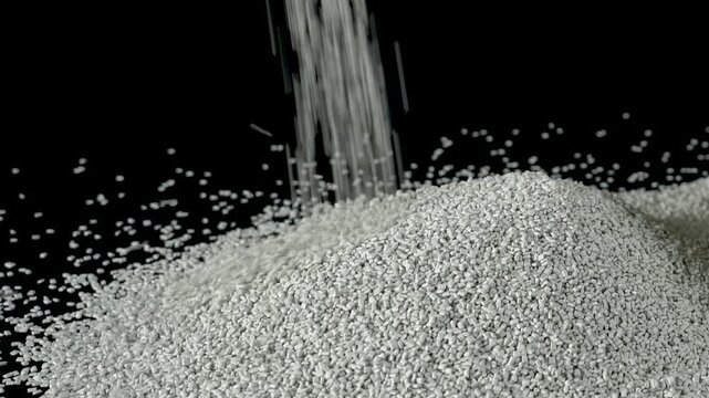 Pouring recycled small plastic raw material granules.