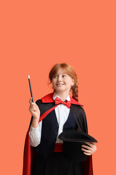 Young magician showing magic trick with hat on orange background