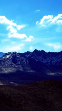 Silhouetted peaks stretch across the landscape, bathed in golden light under a brilliant blue sky. Shadows dance on the slopes, inviting adventure in this serene, untouched wilderness.