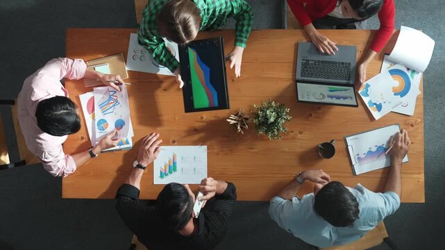 Top down view of business woman explain and present financial chart. Diverse group discuss and listen presentation about stock market statistic at meeting table with investment graph. Convocation.