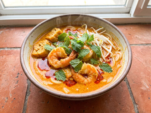Malaysian curry laksa noodle soup with coconut broth prawns tofu puffs bean sprouts and chili oil