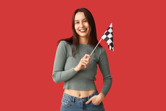Beautiful young woman with racing flag on red background