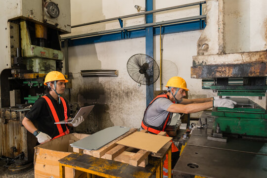 Engineer with laptop consulting machine operator adjusting power press die