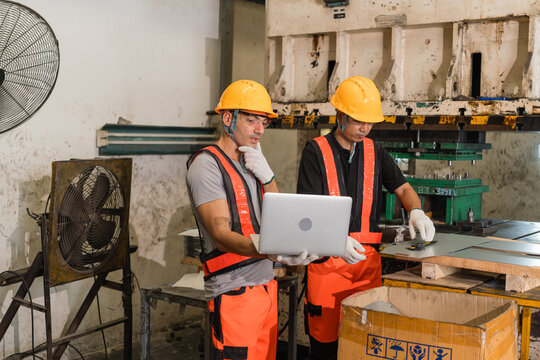 Engineer touching chin thoughtfully while studying laptop screen inside metal stamping factory
