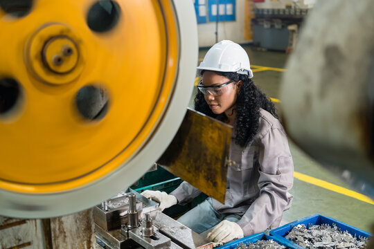 Female engineer inspecting stamping die and tooling on power press highlighting skilled labor and industrial teamwork in the automotive parts manufacturing sector
