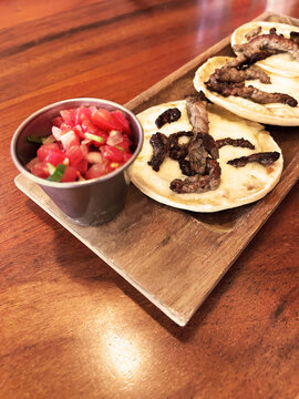 Tortillas con queso derretido y carne asada, acompa&ntilde;adas de tomate picado tipo pico de gallo.