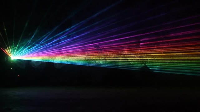 Colorful laser beams sweeping across dark room in landscape video