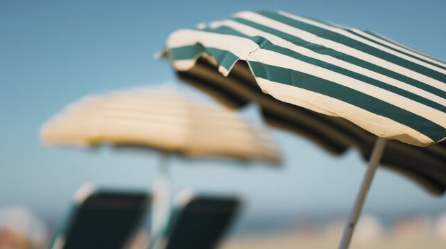 Beach umbrellas stand under the sun on a sandy shore with blue sky in the background during a warm afternoon