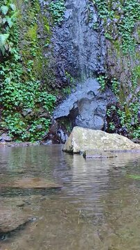 A serene view of Tlogo Muncar Waterfall in Kaliurang, Yogyakarta, Indonesia. This crystal-clear waterfall offers the perfect peaceful atmosphere for themes such as travel, relaxation, wellness.