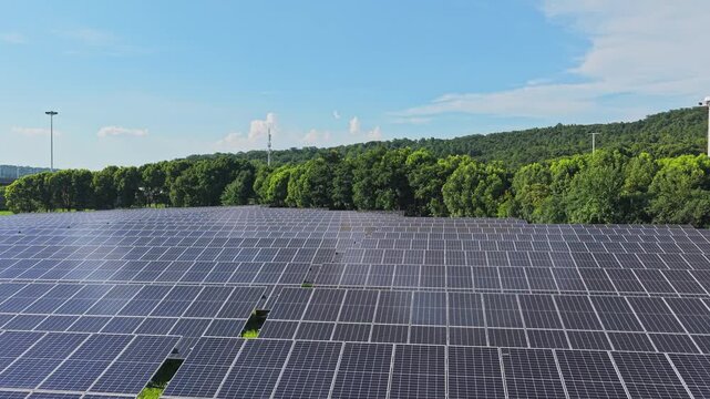 Aerial view gliding across a solar farm and forest edge