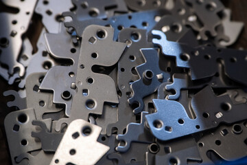 Scattered metal components feature irregular shapes and holes. Close-up view shows various sizes of...