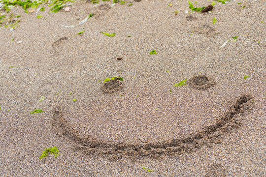Happy Smiley Face Drawn in Sand on a Beach