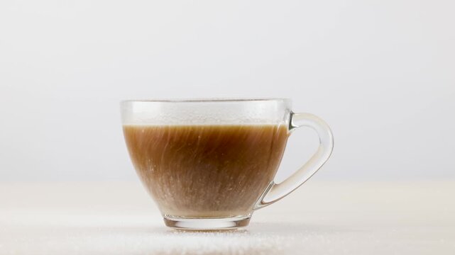 Milk Swirling in Glass Coffee Cup on White Background
