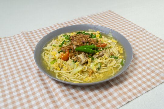 Delicious Indonesian street food Bakmi Godog Jawa, Javanese style boiled noodle soup served in a grey platter, featuring rich flavorful chicken broth