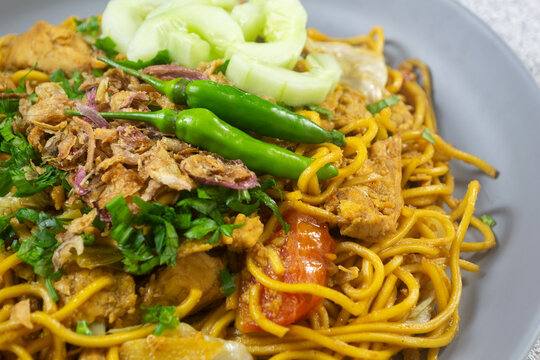 Javanese fried noodles Bakmi Goreng Jawa, stir-fried noodles served with egg, chicken, and cucumber pickles