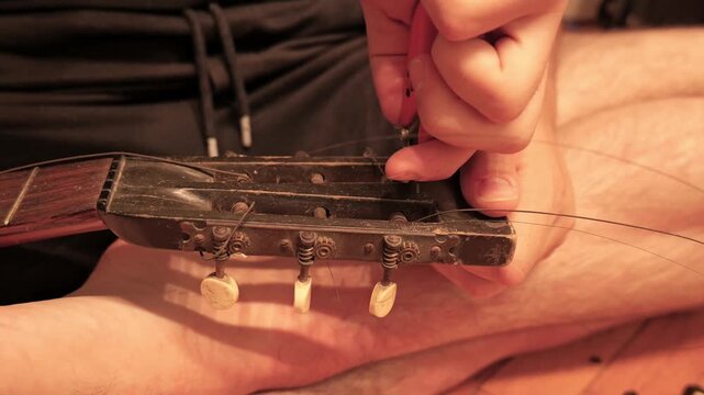 Musician changing strings on old classical guitar