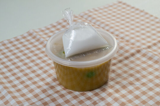Indonesian dessert Bubur Candil packaged in a clear plastic container with a separate bag of coconut milk sauce