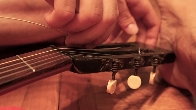 Musician hands changing classical guitar strings