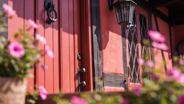 Red timber-framed wall and door with pink flowers in selective focus