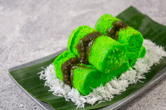 Traditional Indonesian steamed rice flour cake or kue putu bambu filled with melted palm sugar and served over grated coconut on a banana leaf