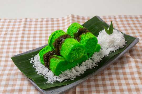 Traditional Indonesian steamed rice flour cake or kue putu bambu filled with melted palm sugar and served over grated coconut on a banana leaf